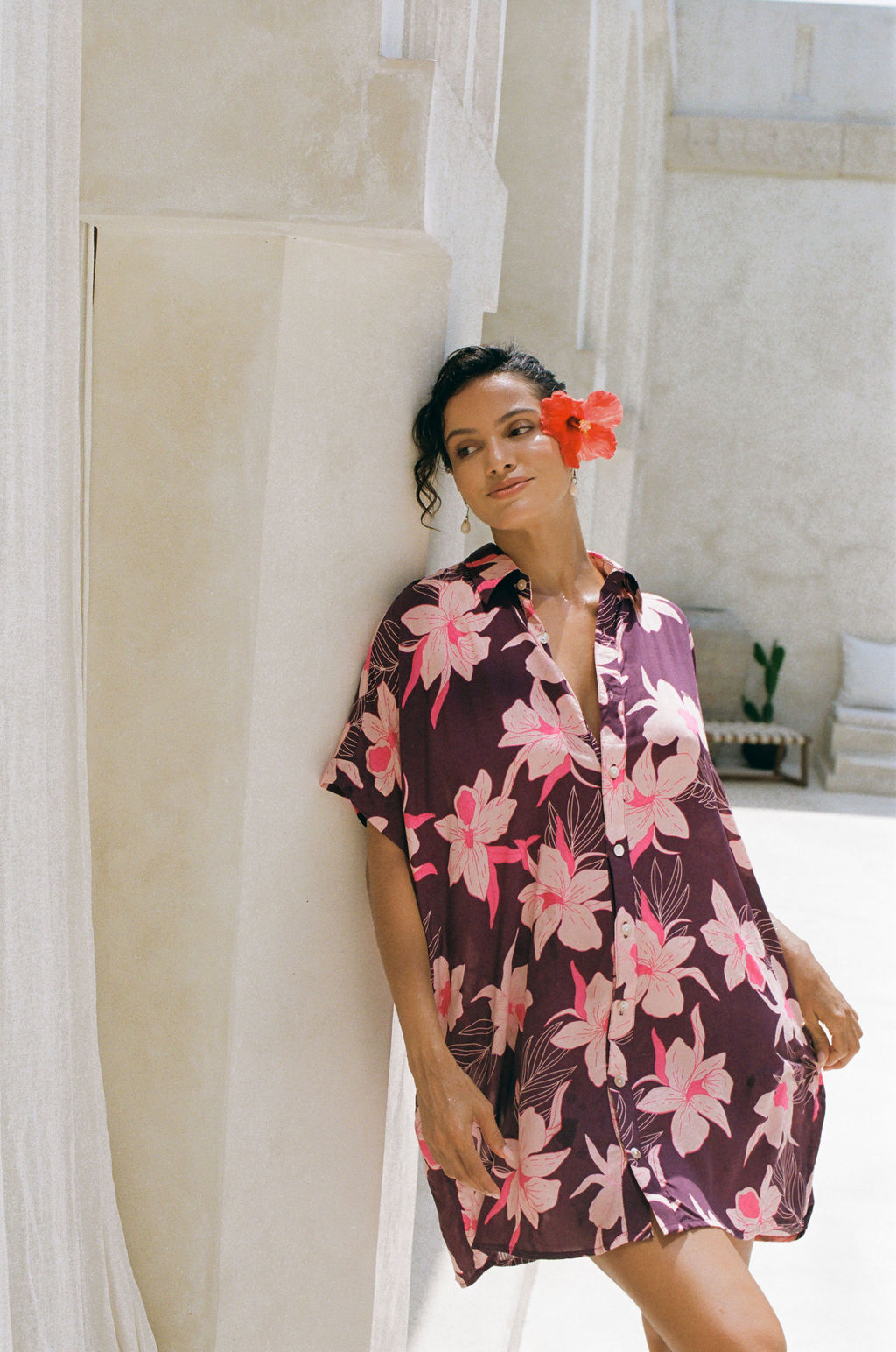 woman wearing an oversized button up shirt dress in dark purple color with orchid print