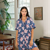 woman with black hair wearing a button up dress in a navy color with pink hibiscus blossoms 