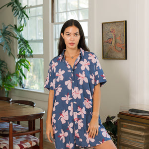 woman with black hair wearing a button up dress in a navy color with pink hibiscus blossoms 