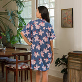 woman with black hair wearing a button up dress in a navy color with pink hibiscus blossoms 