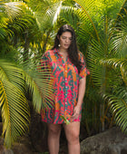 woman with brown hair wearing a colorful button up dress with tropical lei print