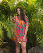 woman with brown hair wearing a colorful button up dress with tropical lei print