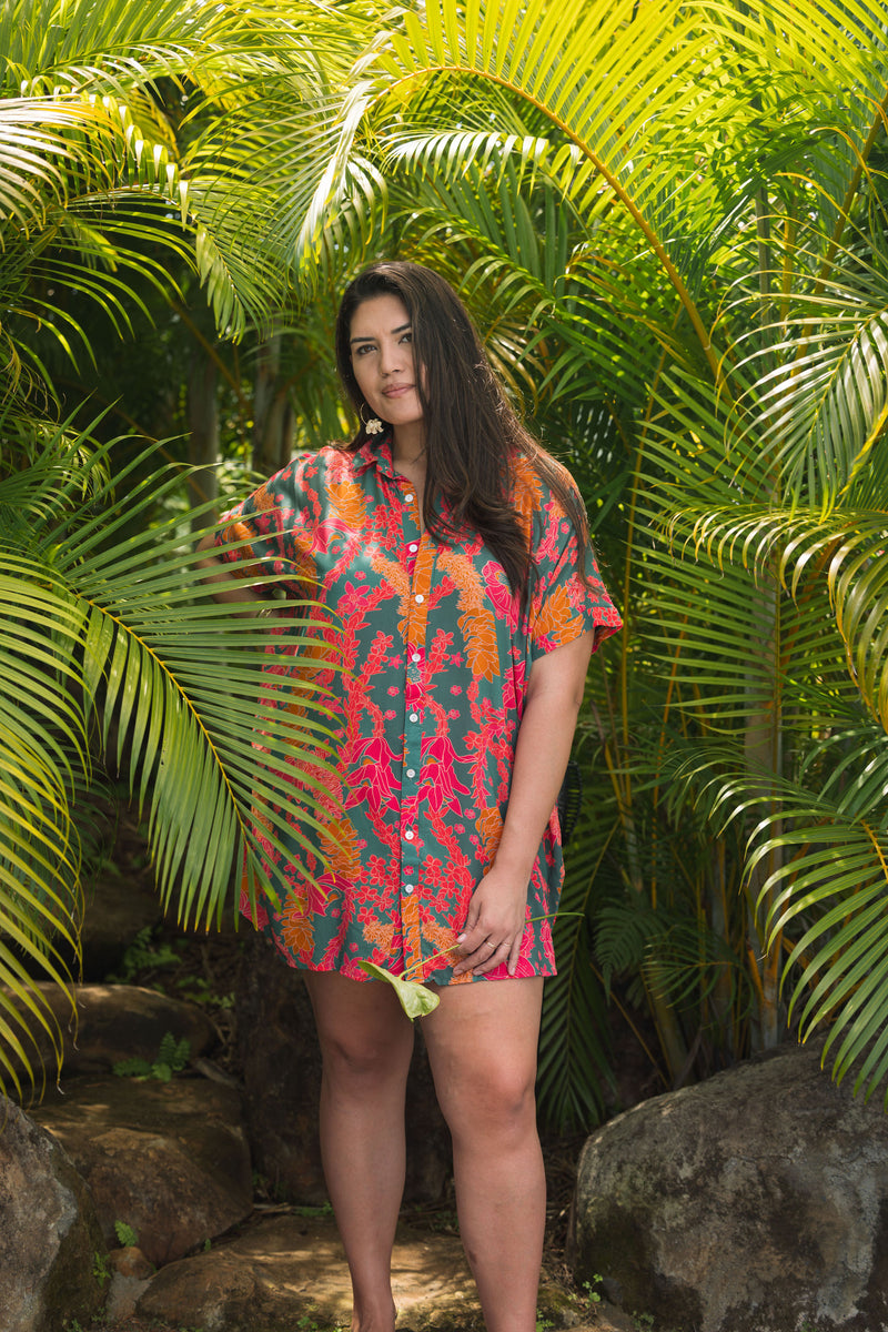 woman with brown hair wearing a colorful button up dress with tropical lei print