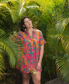 woman with brown hair wearing a colorful button up dress with tropical lei print