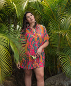 woman with brown hair wearing a colorful button up dress with tropical lei print