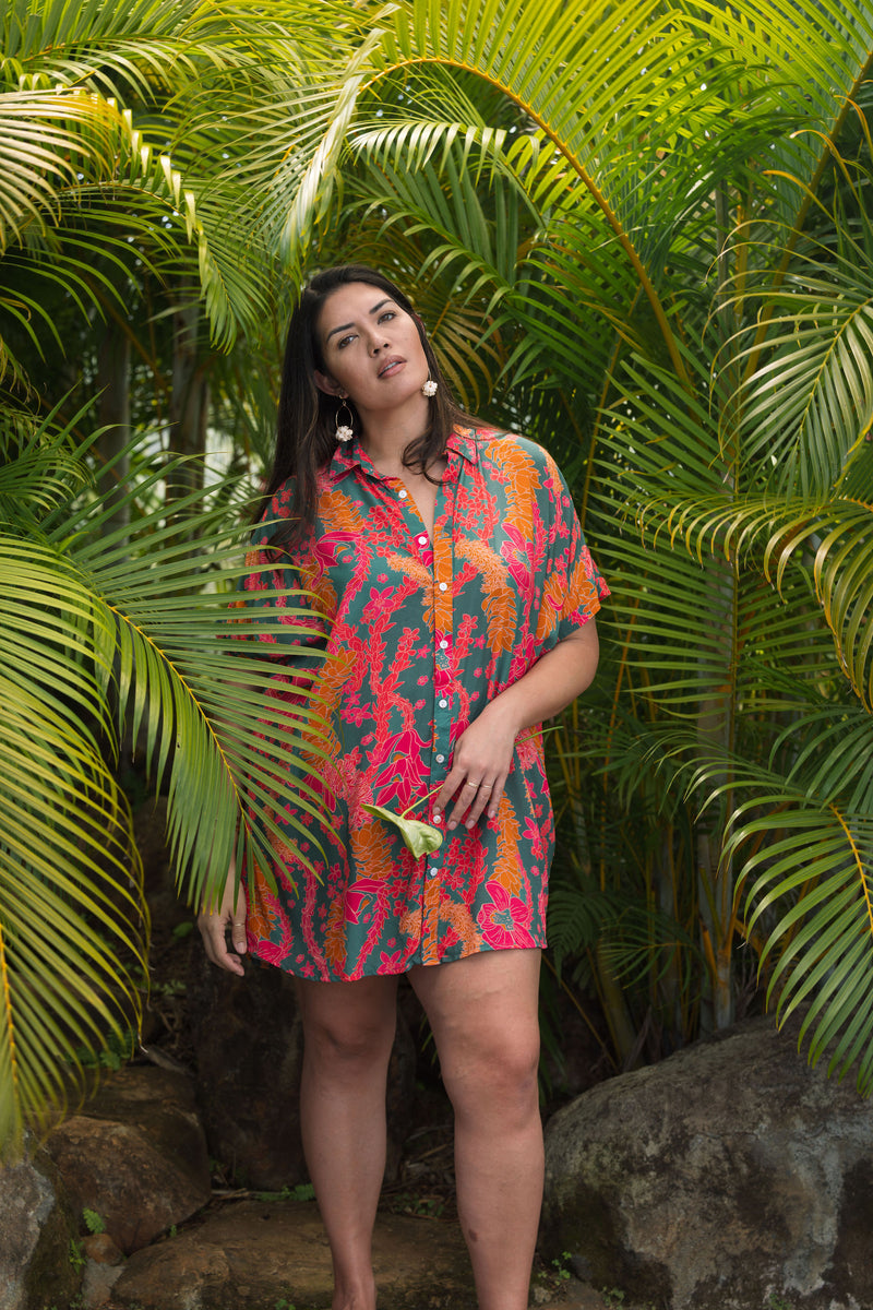 woman with brown hair wearing a colorful button up dress with tropical lei print