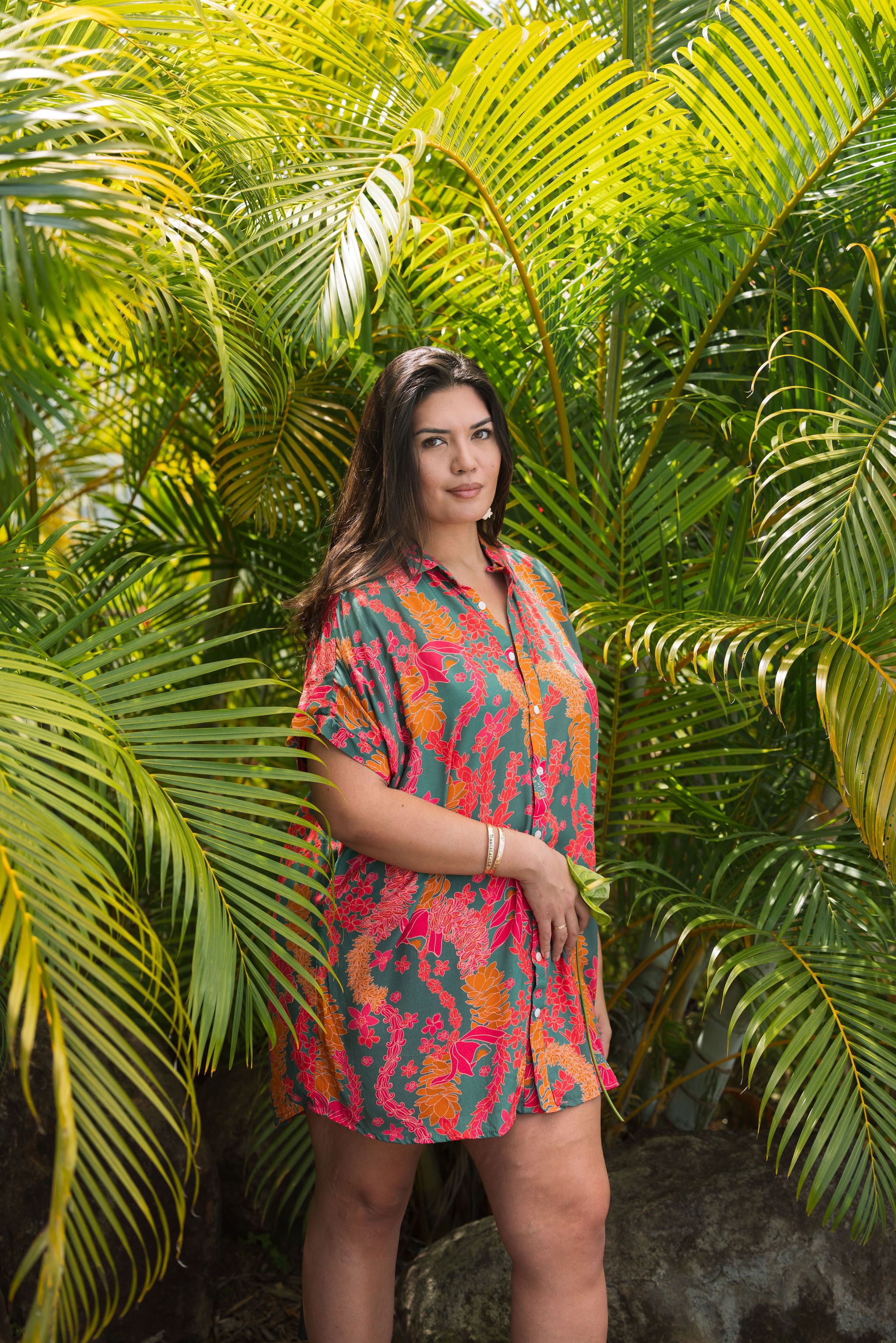 woman with brown hair wearing a colorful button up dress with tropical lei print