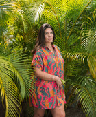 woman with brown hair wearing a colorful button up dress with tropical lei print