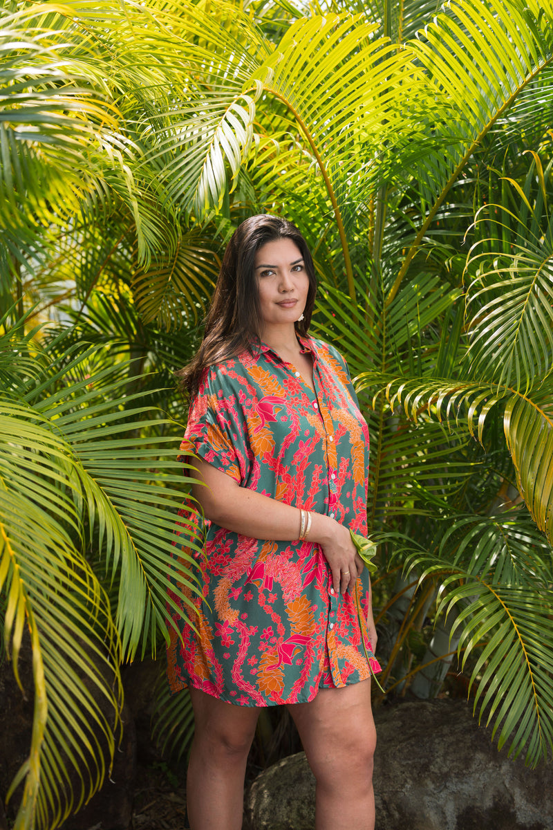 woman with brown hair wearing a colorful button up dress with tropical lei print