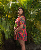 woman with brown hair wearing a colorful button up dress with tropical lei print