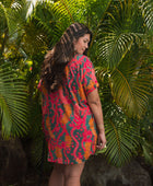 woman with brown hair wearing a colorful button up dress with tropical lei print
