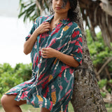 woman with brown hair wearing dark teal button up dress with shell lei print