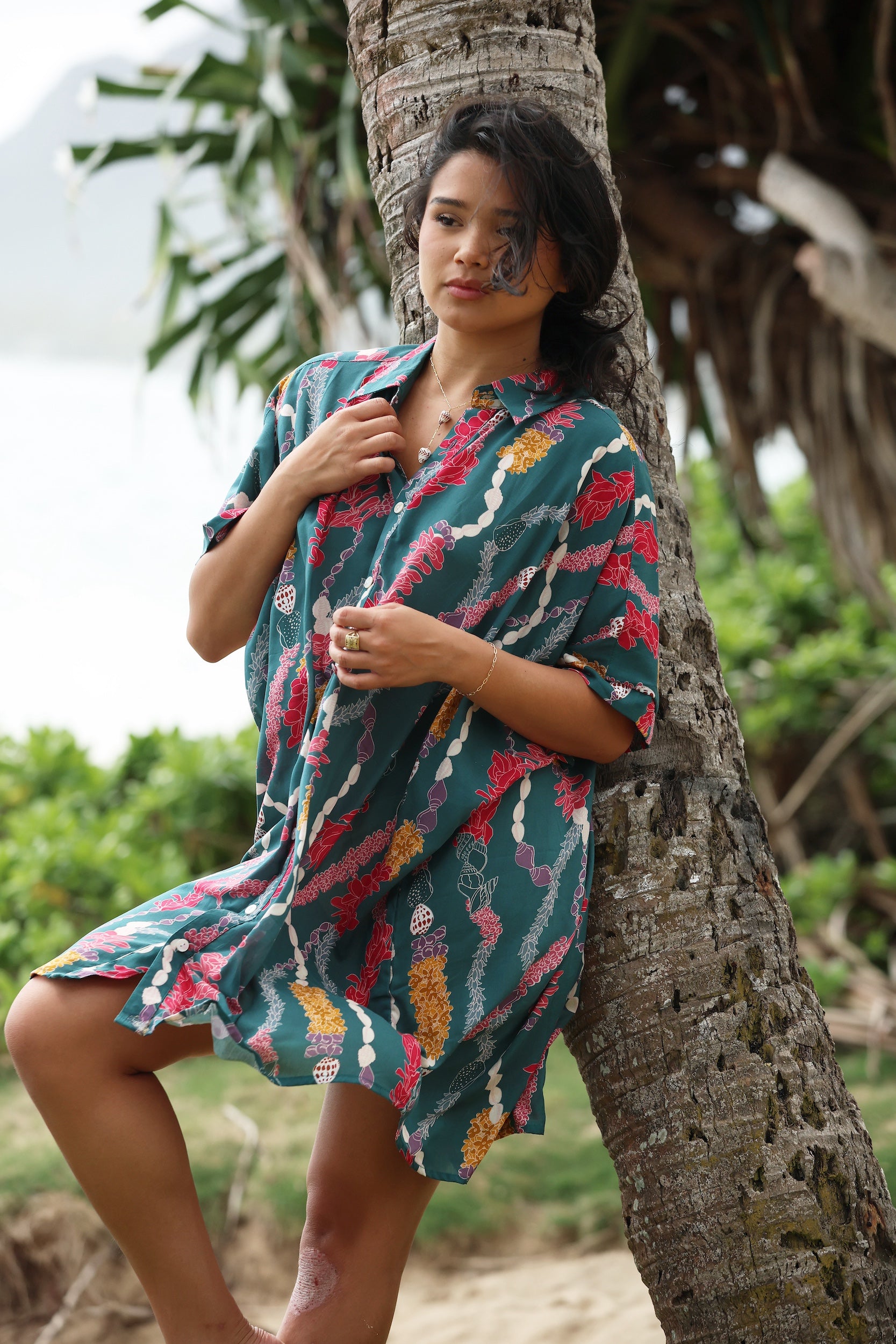 woman with brown hair wearing dark teal button up dress with shell lei print