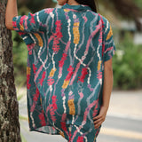 woman with brown hair wearing dark teal button up dress with shell lei print