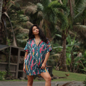 woman with brown hair wearing dark teal button up dress with shell lei print