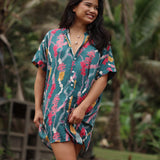 woman with brown hair wearing dark teal button up dress with shell lei print