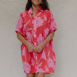 woman with brown hair wearing a red button up collared dress with pink mao flower pattern