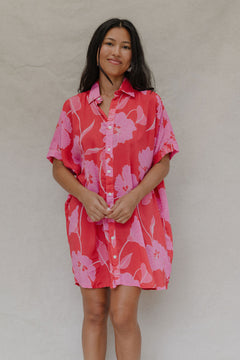 woman with brown hair wearing a red button up collared dress with pink mao flower pattern