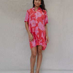 woman with brown hair wearing a red button up collared dress with pink mao flower pattern