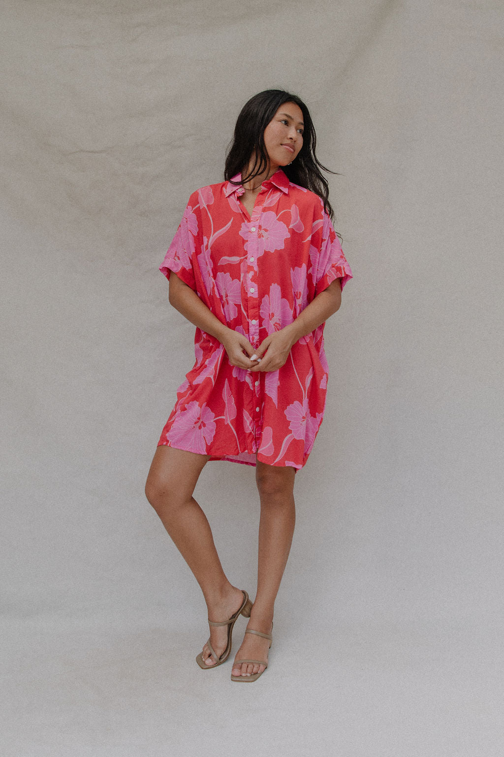 woman with brown hair wearing a red button up collared dress with pink mao flower pattern