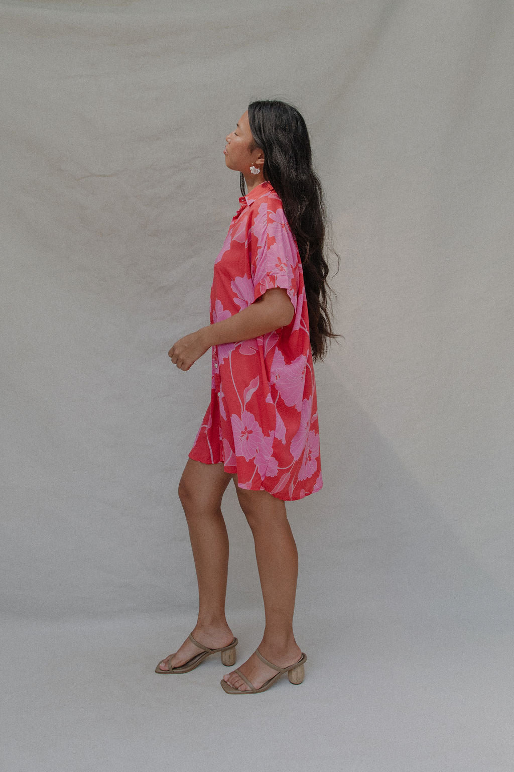 woman with brown hair wearing a red button up collared dress with pink mao flower pattern