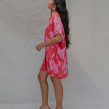 woman with brown hair wearing a red button up collared dress with pink mao flower pattern