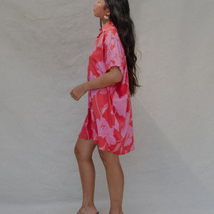 woman with brown hair wearing a red button up collared dress with pink mao flower pattern