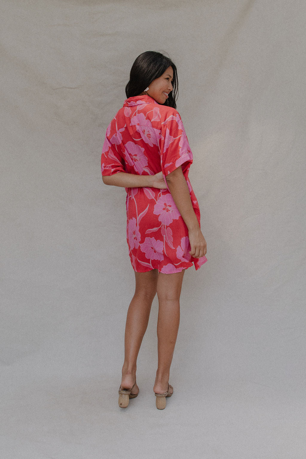 woman with brown hair wearing a red button up collared dress with pink mao flower pattern