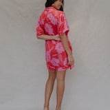 woman with brown hair wearing a red button up collared dress with pink mao flower pattern