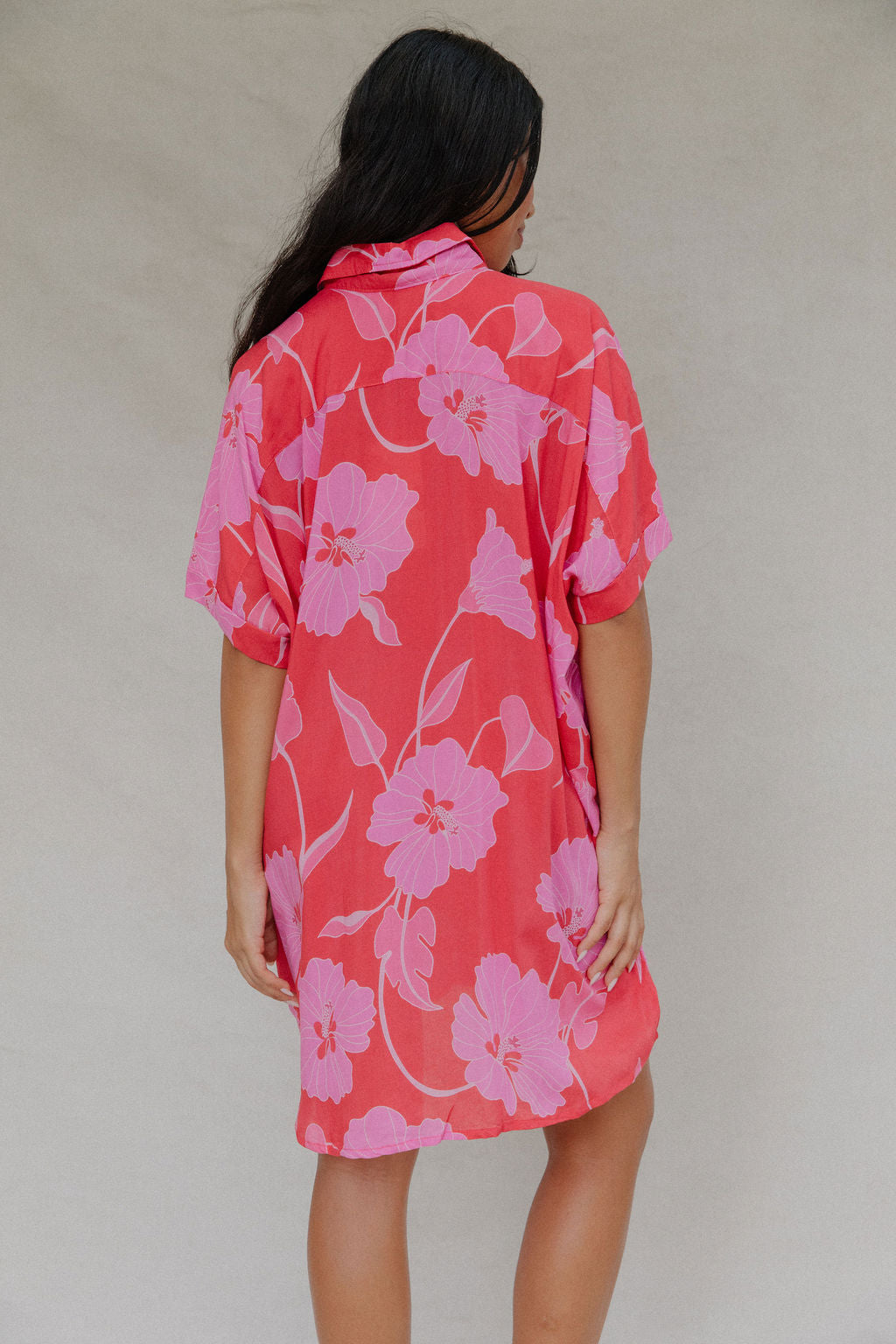 woman with brown hair wearing a red button up collared dress with pink mao flower pattern