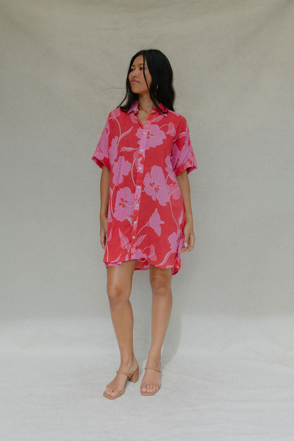 woman with brown hair wearing a red button up collared dress with pink mao flower pattern