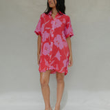 woman with brown hair wearing a red button up collared dress with pink mao flower pattern