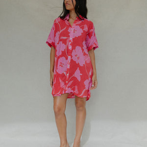 woman with brown hair wearing a red button up collared dress with pink mao flower pattern