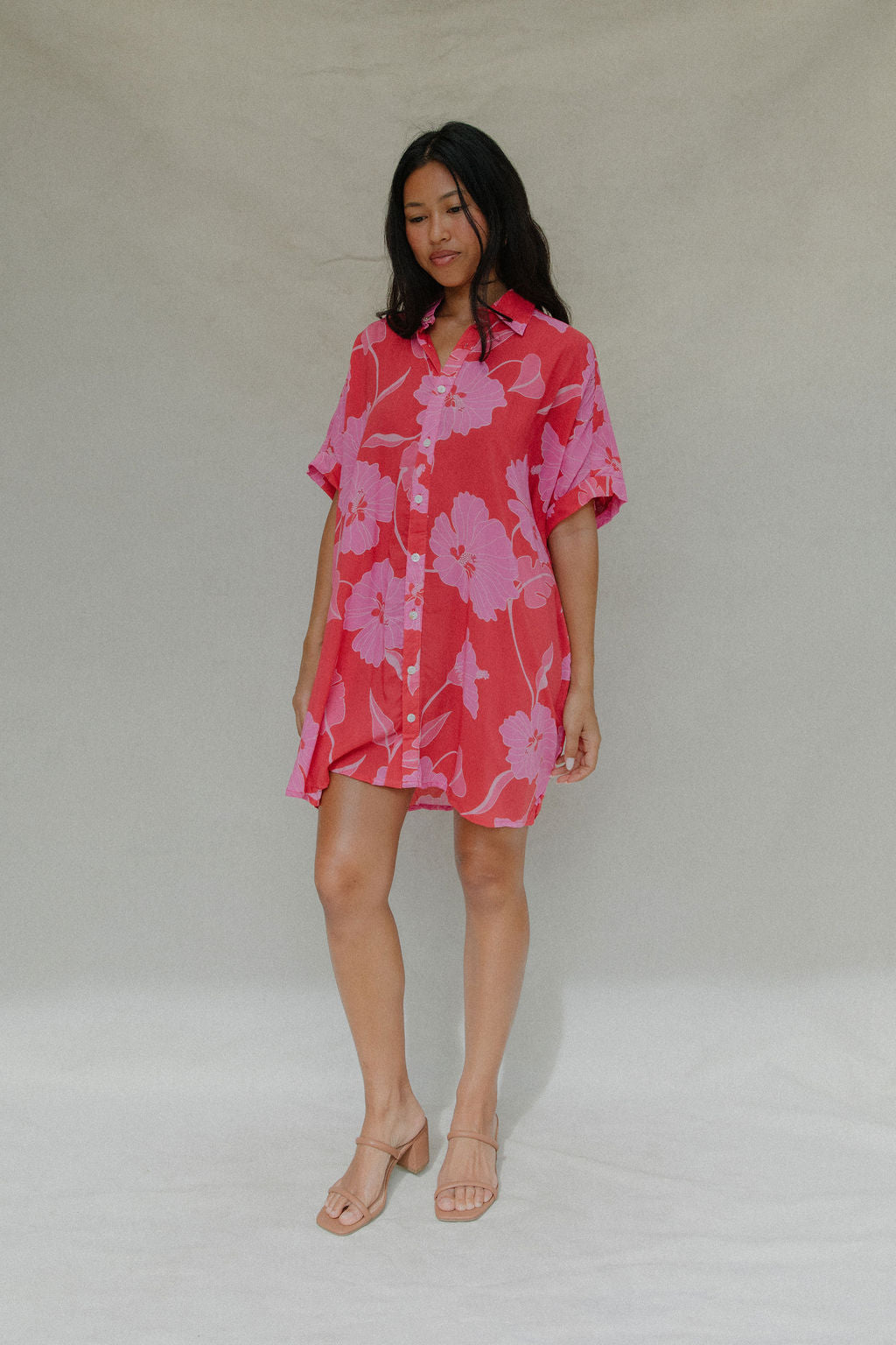woman with brown hair wearing a red button up collared dress with pink mao flower pattern
