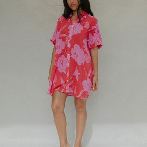 woman with brown hair wearing a red button up collared dress with pink mao flower pattern