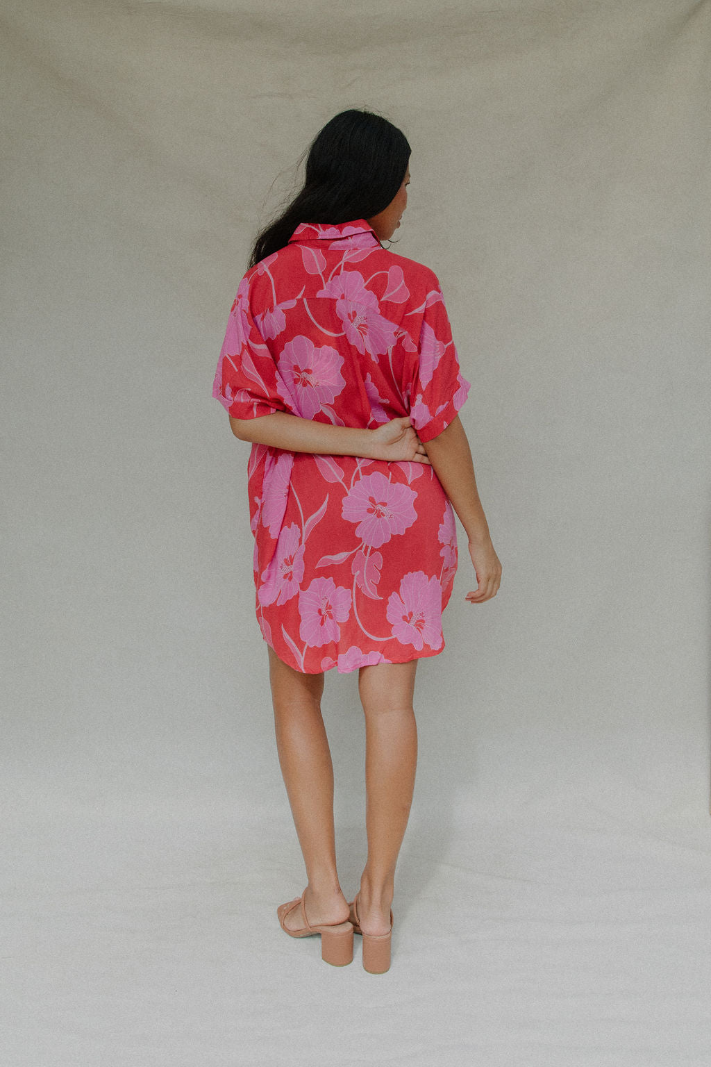 woman with brown hair wearing a red button up collared dress with pink mao flower pattern
