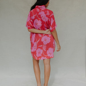 woman with brown hair wearing a red button up collared dress with pink mao flower pattern