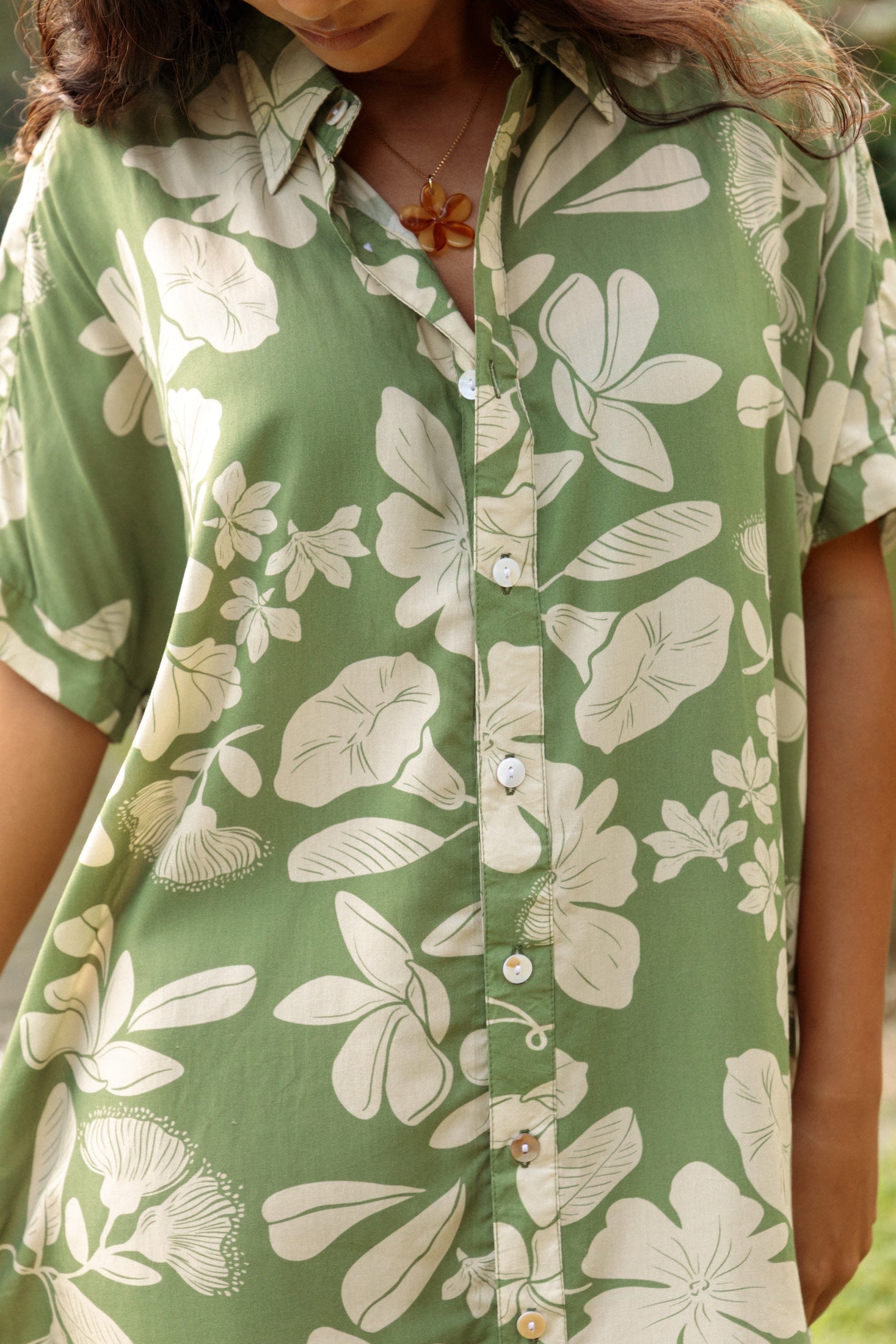 woman with brown hair wearing green collared button up dress with native Hawaiian plants