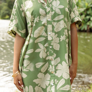 woman with brown hair wearing green collared button up dress with native Hawaiian plants
