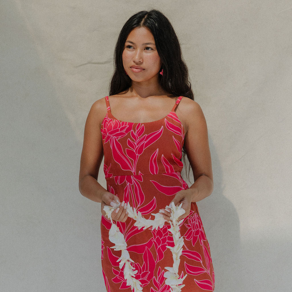 woman with brown hair wearing a sienna colored mini dress with tie back detail and awapuhi pattern