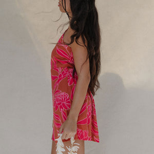 woman with brown hair wearing a sienna colored mini dress with tie back detail and awapuhi pattern