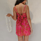 woman with brown hair wearing a sienna colored mini dress with tie back detail and awapuhi pattern