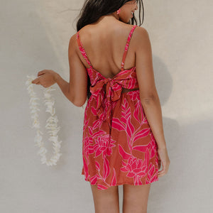 woman with brown hair wearing a sienna colored mini dress with tie back detail and awapuhi pattern