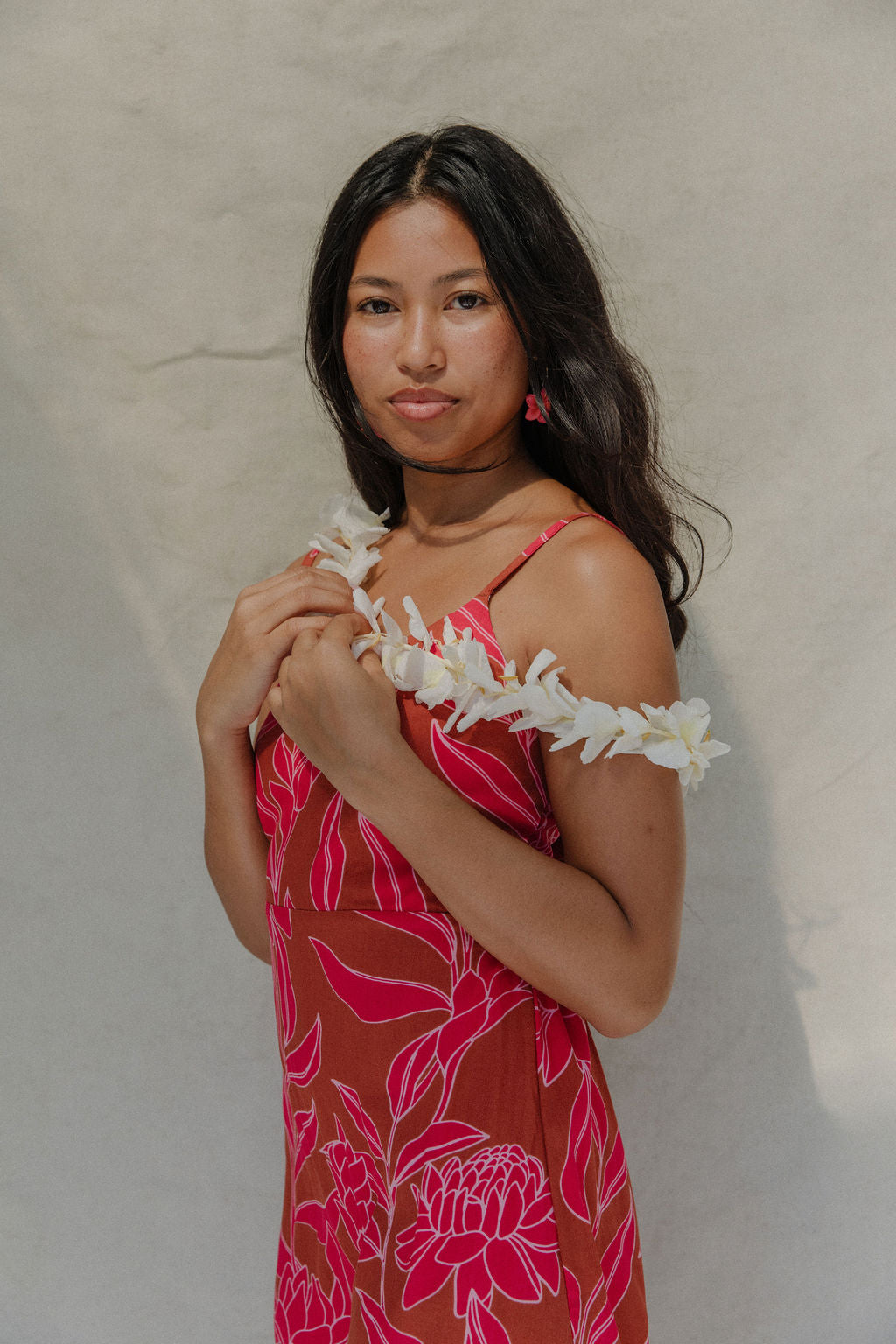 woman with brown hair wearing a sienna colored mini dress with tie back detail and awapuhi pattern