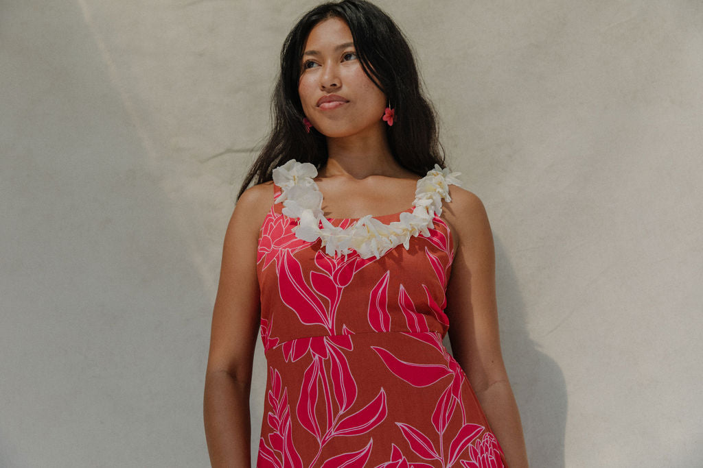 woman with brown hair wearing a sienna colored mini dress with tie back detail and awapuhi pattern