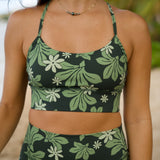 woman with brown hair wearing dark green active sports bra and 4.5 inch shorts with naupaka tiare print