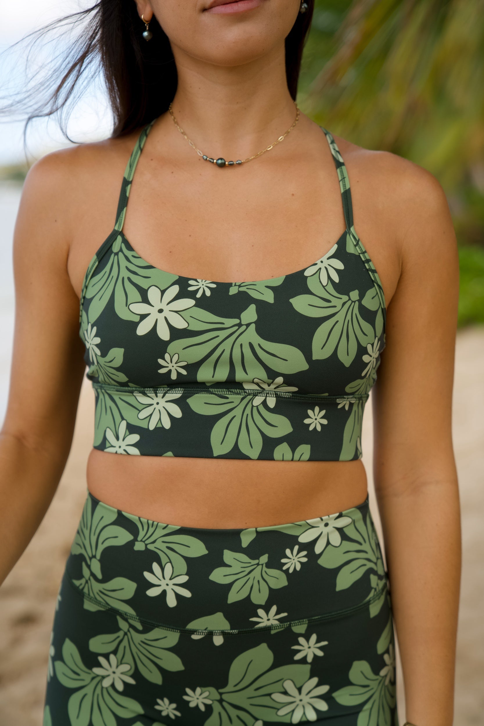 woman with brown hair wearing dark green active sports bra and 4.5 inch shorts with naupaka tiare print