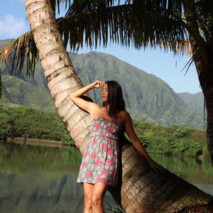 woman with brown hair wearing a teal mini dress with removable straps and smocked bodice with shell and pua print