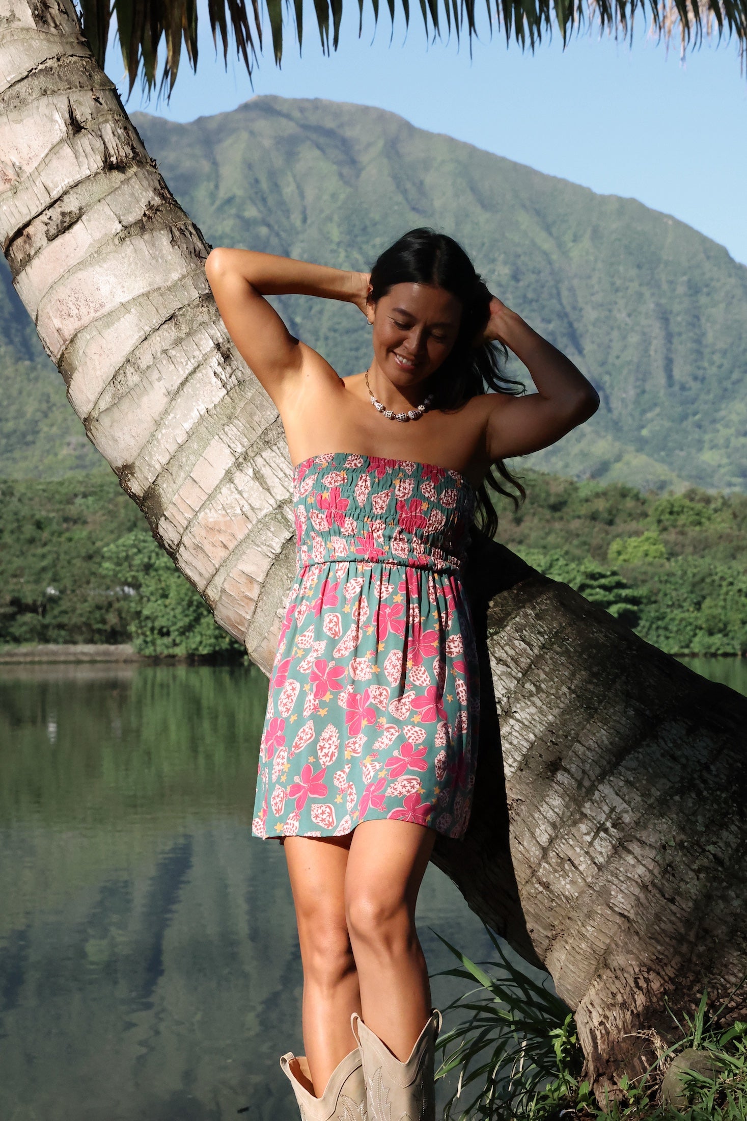 woman with brown hair wearing a teal mini dress with removable straps and smocked bodice with shell and pua print