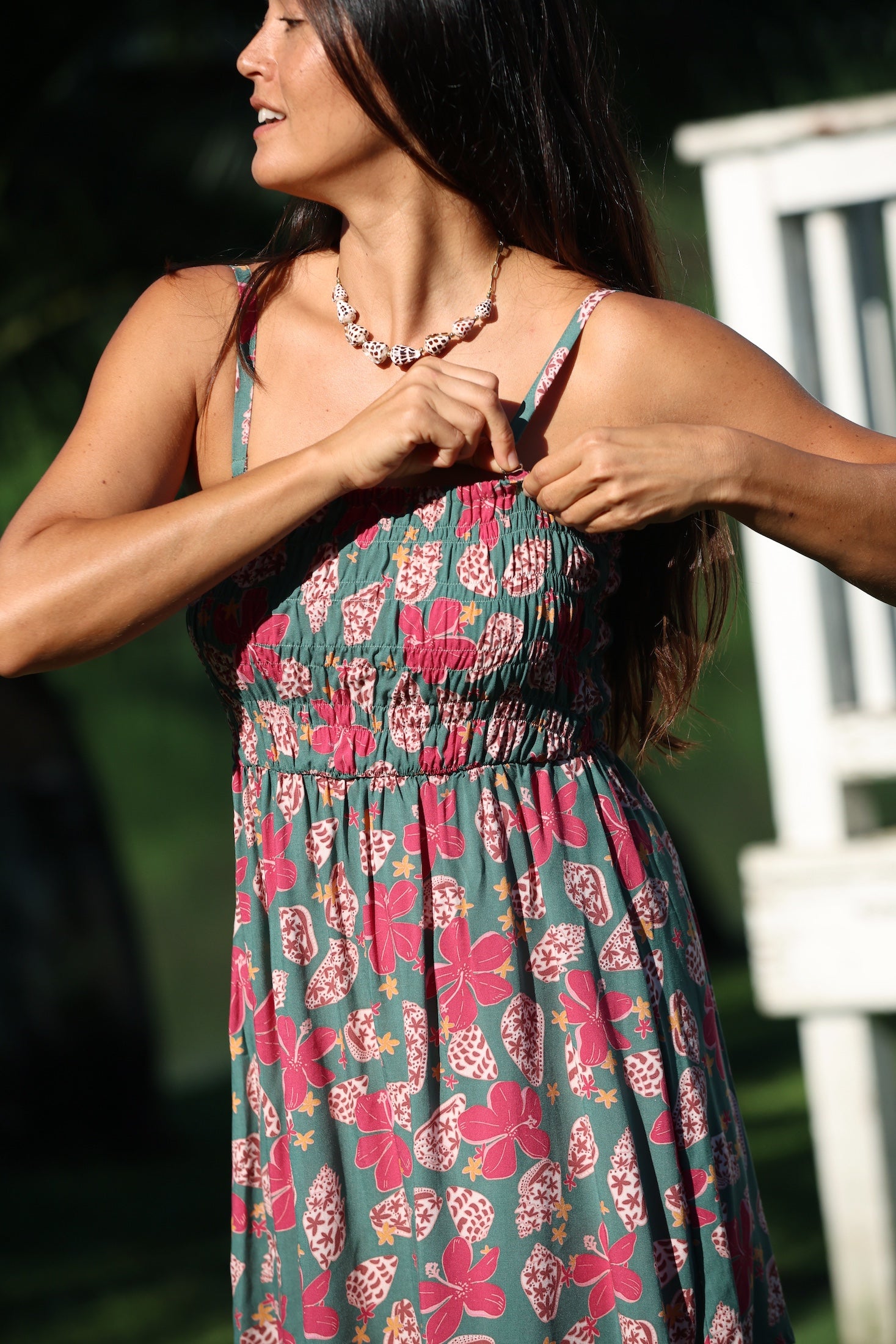 woman with brown hair wearing a teal mini dress with removable straps and smocked bodice with shell and pua print